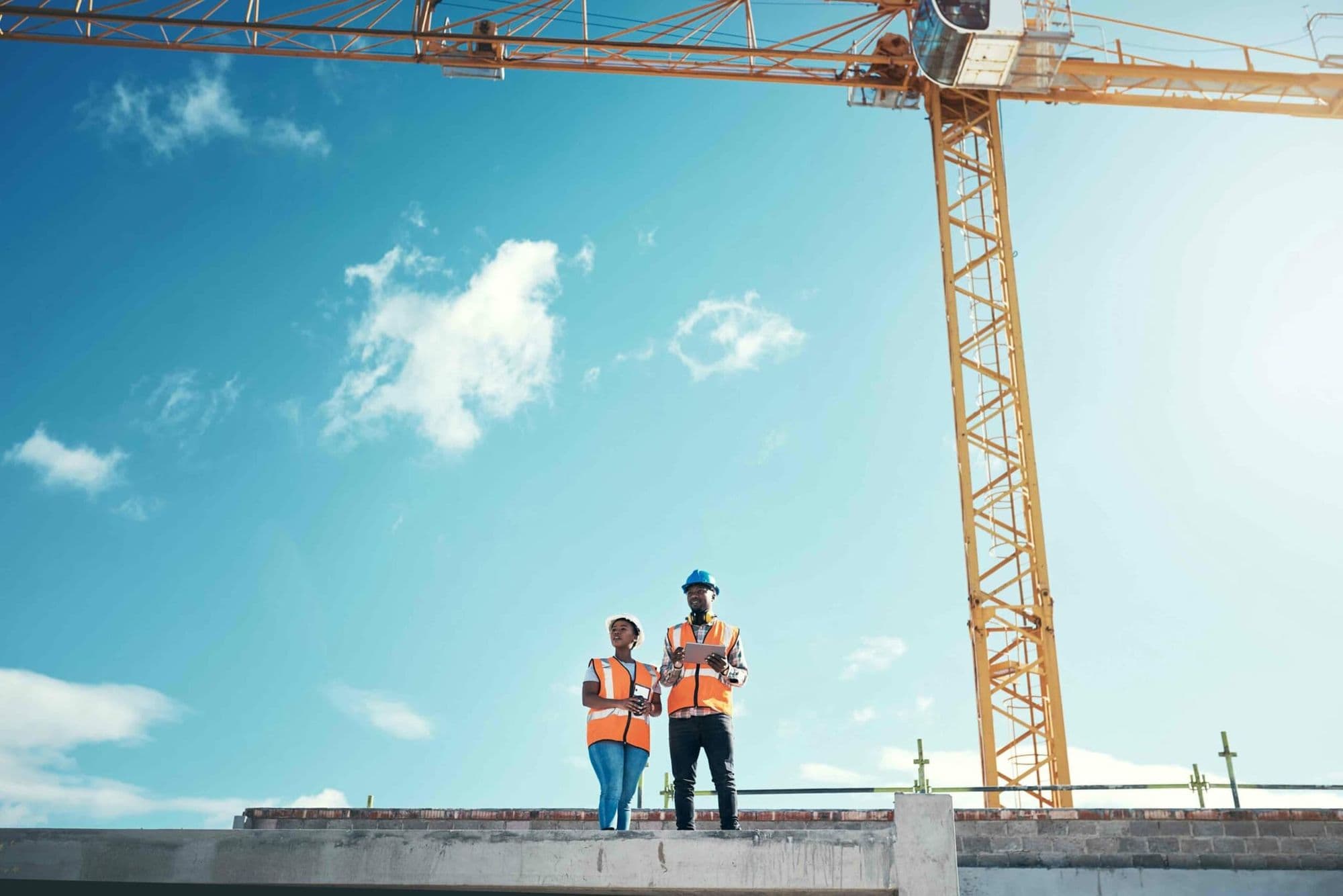 Site team in high-visibility vests planning emergency procedures beside a crane