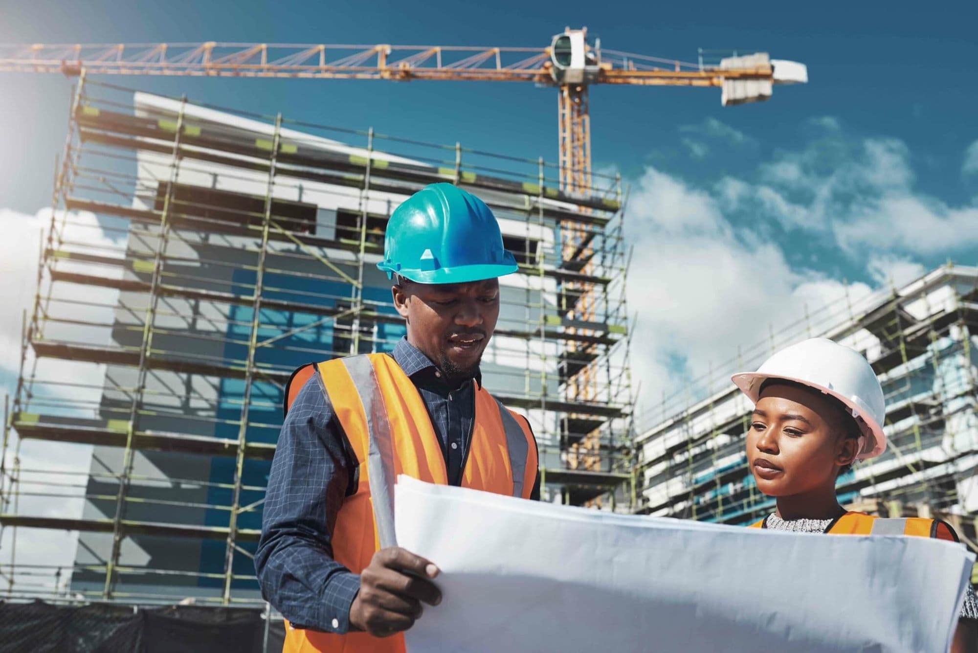 Health and safety consultants in hard hats reviewing plans on a construction site