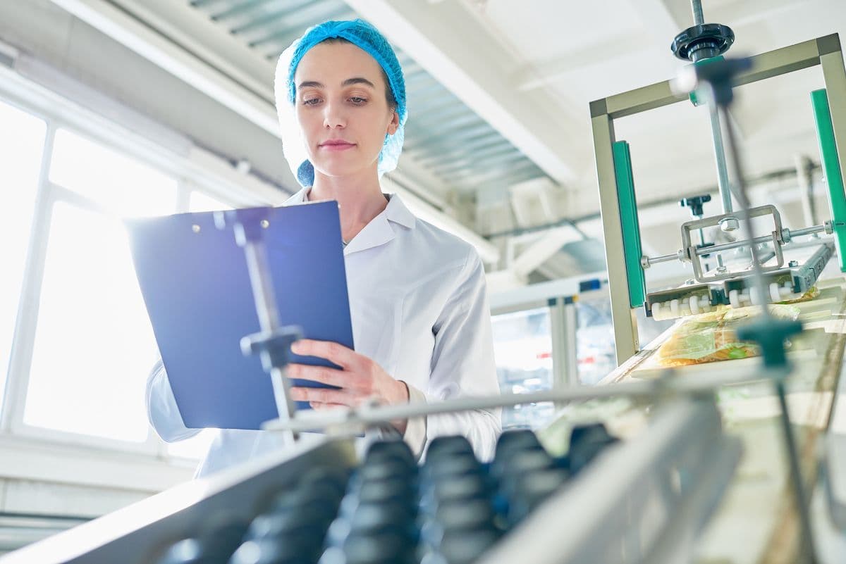 Quality controller with a clipboard inspecting a production line