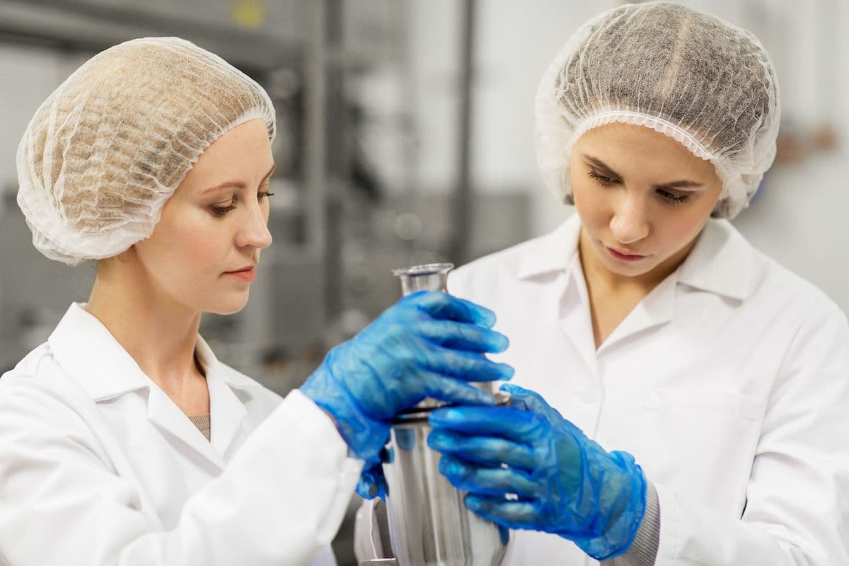 Food technologists in gloves and hairnets testing samples