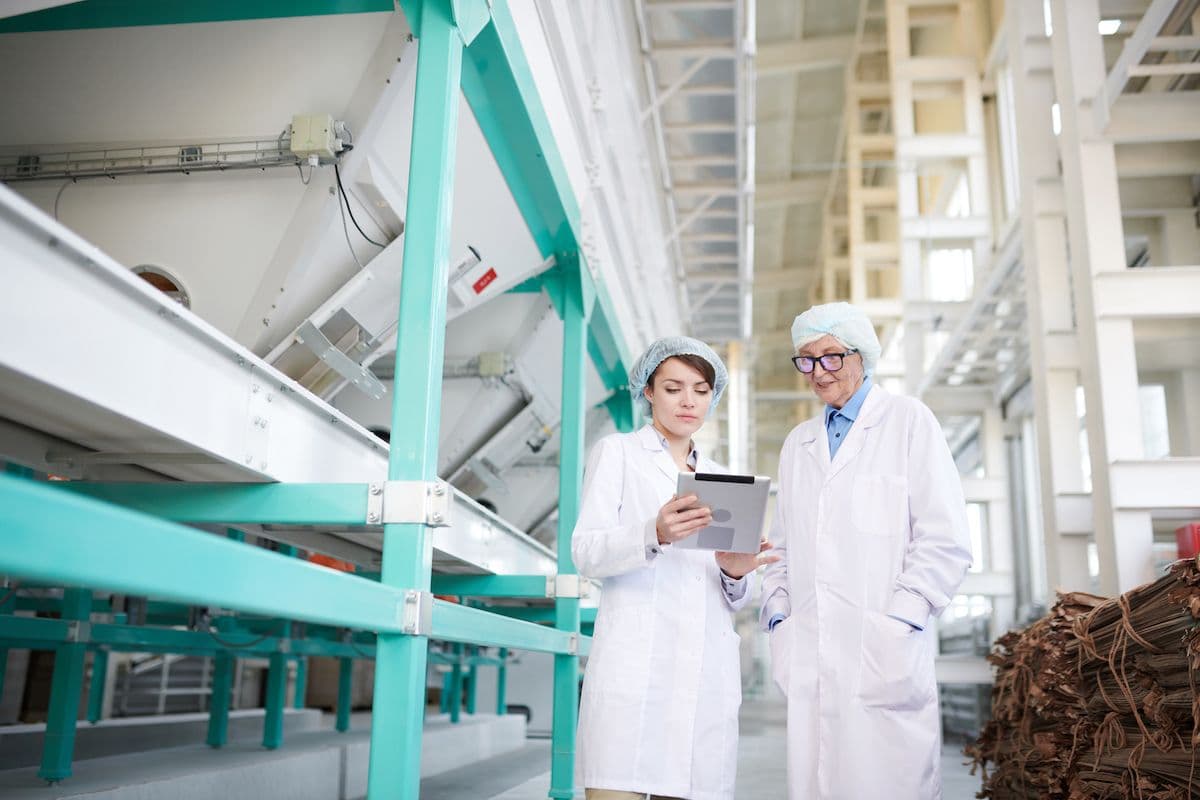 Auditors with a tablet reviewing findings in a food processing plant