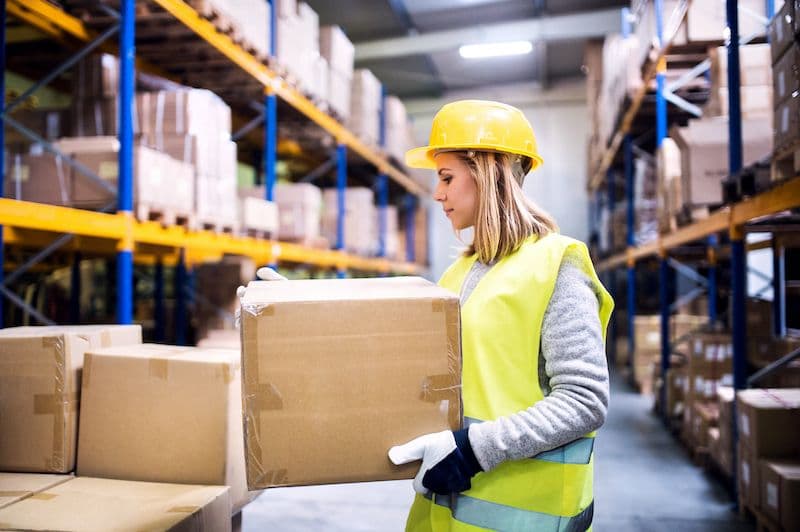 Warehouse worker in a hard hat and vest loading boxes safely
